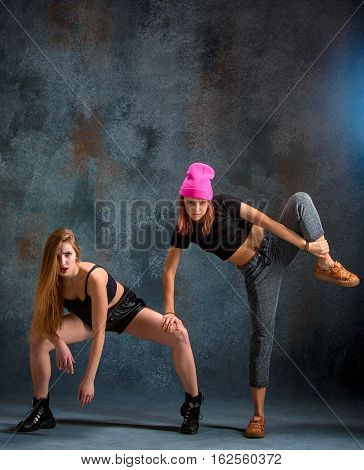 The two attractive girls dancing twerk iat the blue studio background