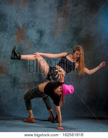 The two attractive girls dancing twerk iat the blue studio background