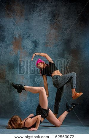 The two attractive girls dancing twerk iat the blue studio background