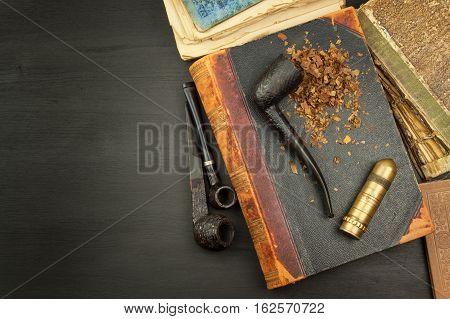Smoking pipe and antique books. Tobacco pipe on ancient books. Relax by reading old books. Smoking. Risk of cancer.