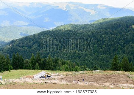 Horizontal view with sheepfold and mountains. Wooden sheepfold in Carpathians near mountain range.