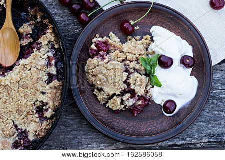 Homemade Cherry crumble wiht ice cream and cherries on an old wooden table background.Selective focus.
