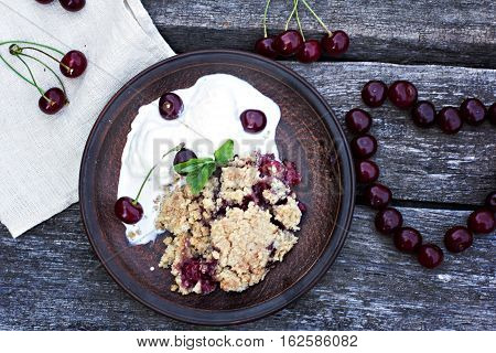 Homemade Cherry crumble wiht ice cream and cherries on an old wooden table background.Selective focus.