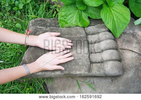 Female Hand Praying On Top Of Big Buddha Hand