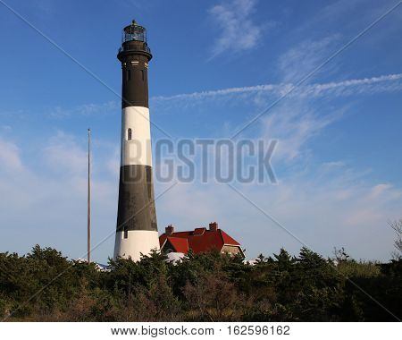 Fire Island Lighthouse with a deep blue sky and some light clouds behind it.