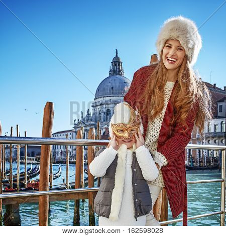 Mother And Child Tourists On Embankment Wearing Venetian Mask
