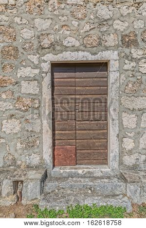 Brown old wooden door of the typical house in Tucepi village, Croatia.