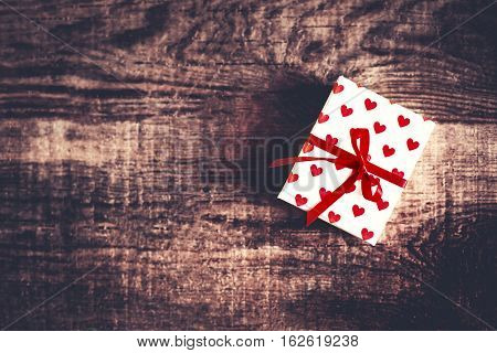 Valentines Day gift box on old vintage wooden background with red Hearts and red ribbon with blank copyspace for greeting text