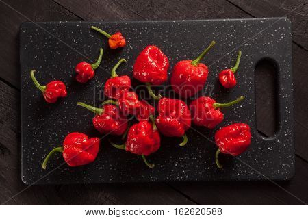 Red hot Trinidad moruga scorpion peppers on black cutting board