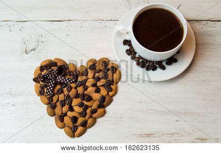 White plate in the form of seashells with coffee beans, cinnamon sticks and star anise, a festive tablecloth and cup with saucer on a dark wooden background.