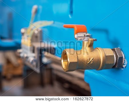 Half inch brass ball valve in industrial setting. Shallow depth of field with the valve in focus.