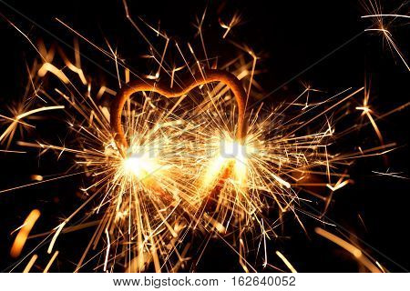 Macro photo of a burning sparkler in form of a heart.