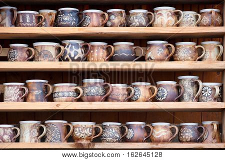different handmade decorated coffee mugs and tea standing on the shelves