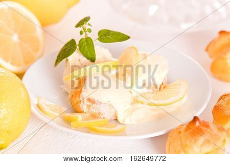 Profiteroles with lemon cream on white dish.