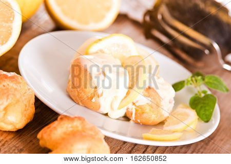 Profiteroles with lemon cream on white dish.