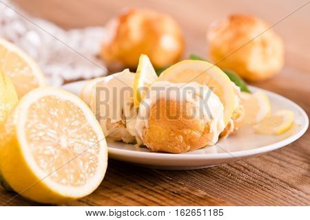 Profiteroles with lemon cream on white dish.