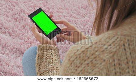 Woman looking at smartphone with green screen. Close up shot of woman's hands with mobile