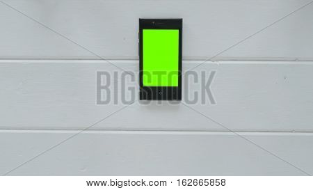 Smartphone with green screen on white wooden background