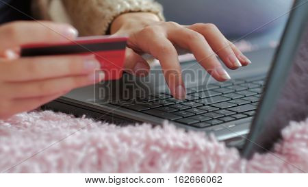 Close up shot. Young woman buying goods from the internet and entering number security code from credit card on laptop. Online, technology and internet concept.