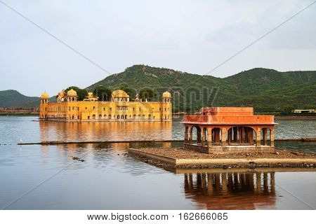 Jaipur India. Jal Mahal palace in the evening in Jaipur India. Popular landmark surrounded by water. Mountains at the background