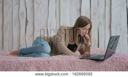 Woman lying on the bed and using laptop. Business, communication, freelance and internet concept