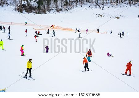 BUKOVEL, UKRAINE - December 17, 2016: Snowboarder and skiers enjoying on slopes of ski resort Bukovel. Bukovel is the most popular ski resort in Ukraine. Ski season and Winter sports concept