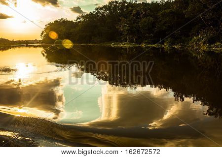 Reflection of the sun at sunset in the Limoncocha lagoon in the Ecuadorian Amazon