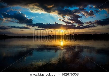 Reflection of the sun at sunset in the Limoncocha lagoon in the Ecuadorian Amazon