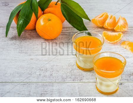 Delicious and rich in vitamins panna cotta with tangarine jam tangarines and slice of tangarines on a white wooden table