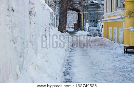 Snow-covered narrow street with arch in the daytime