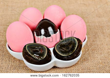Thousand egg Preserving Duck on white cup on sack background.
