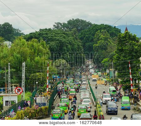 traffic jam in bogor station with a lot of local public transportation and mountain as background in bogor indonesia photo