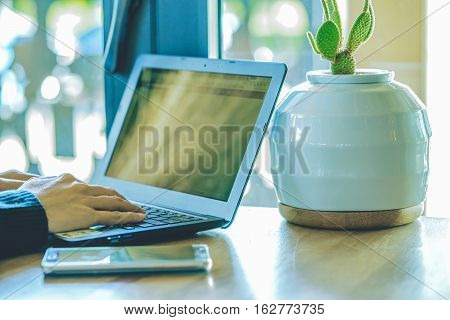 Businesswoman's hands using laptop computer with defocused smart-phone in foreground working with modern devices smartphone and laptop computer in coffee shop woman using technology .