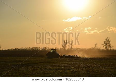 Tractor At Sunset Plow Plow A Field. Tilling The Soil In The Fall After Harvest. The End Of The Seas