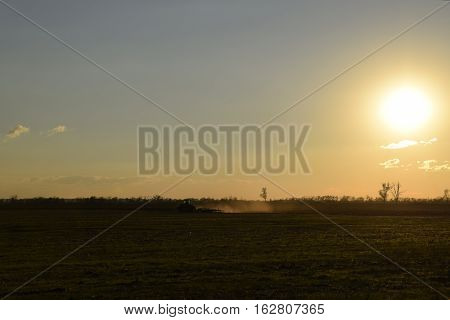 Tractor At Sunset Plow Plow A Field. Tilling The Soil In The Fall After Harvest. The End Of The Seas