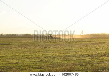Tractor At Sunset Plow Plow A Field. Tilling The Soil In The Fall After Harvest. The End Of The Seas
