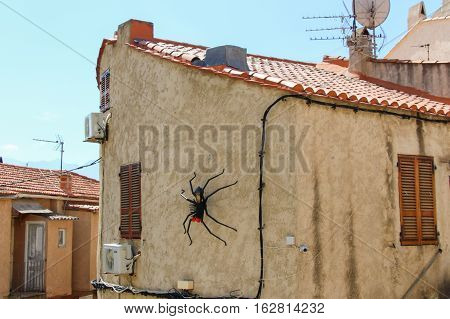 The view of artificial spider on a building in a sunny day. Corse France.