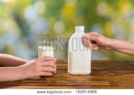 Mother hands with botlle of milk and child's hands glass