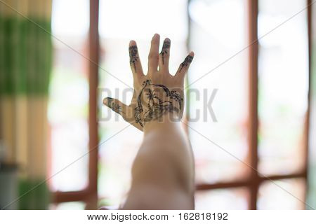 female hand with painted mehendi on blurred background