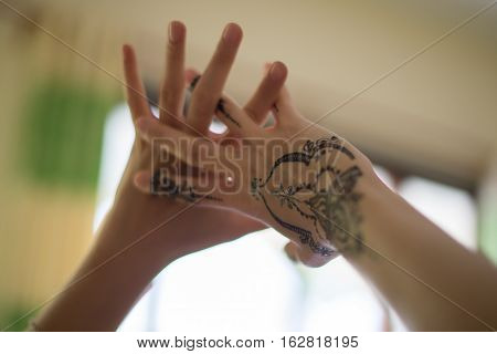 two female hands with painted mehendi on blurred background