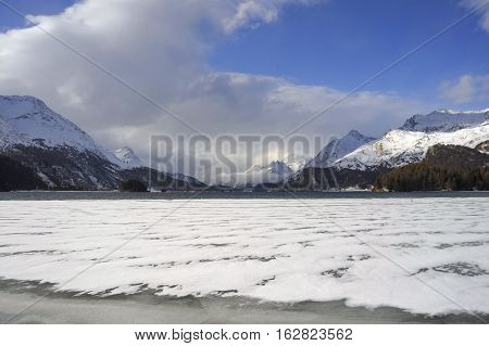 amazing landscape scenic view of Engadin valley in Switzerland Sils Maria village with snow on Alp mountains and frozen lake on a cold sunny winter day in tourism and holiday destination