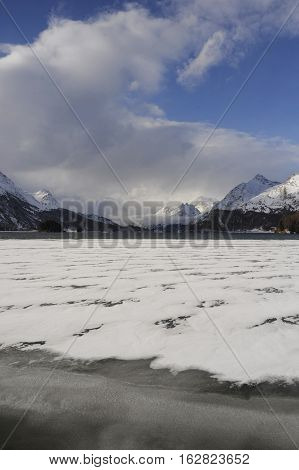 amazing landscape scenic view of Engadin valley in Switzerland Sils Maria village with snow on Alp mountains and frozen lake on a cold sunny winter day in tourism and holiday destination