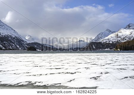 amazing landscape scenic view of Engadin valley in Switzerland Sils Maria village with snow on Alp mountains and frozen lake on a cold sunny winter day in tourism and holiday destination