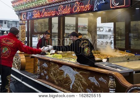 Istanbul Turkey - March 29 2013: Eating Grilled Fish Sandwich in Eminonu. The first thing that comes to mind when thinking of Istanbul is Eminonu-Karakoy and the places selling grilled fish sandwiches on the bank of Golden Horn there. Men wearing richly d