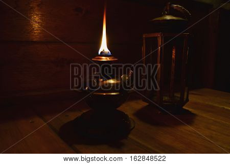 a copper kerosene lamp burns on a table in a night-time
