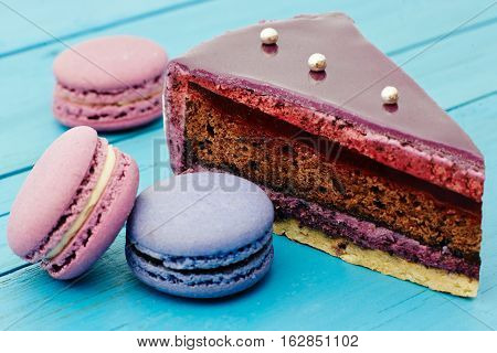 Sweet piece of cake and macaron on wooden table