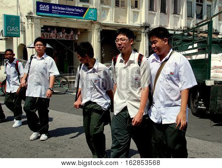 Georgetown Malaysia - January 8 2008: A group of Malaysian schoolboys wearing uniforms of green-gray trousers and short-sleeved white shirts walking on Lebuh Kimberley