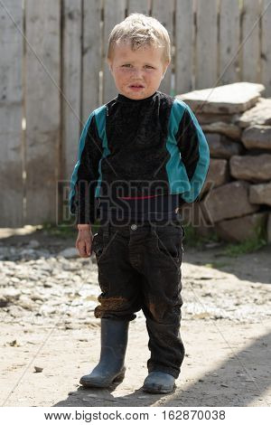 STINKA UKRAINE - APRIL 14 2016 - funny little pig boy dressed stands in a yard in rubber boots on April 14 2016 in Stinka village.