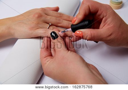 Professional manicurist applying liquid acrylic to nail extensions