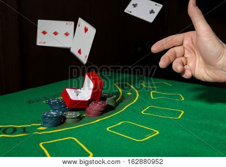 casino chips and a precious ring on a green poker table background, man throws cards with losing combination